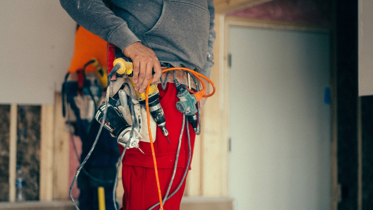 Construction worker organizing tools on tool belt inside renovation job site.