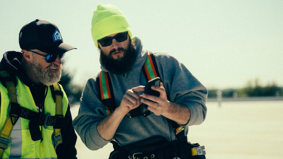 Contractors review project photos in mobile job site app.