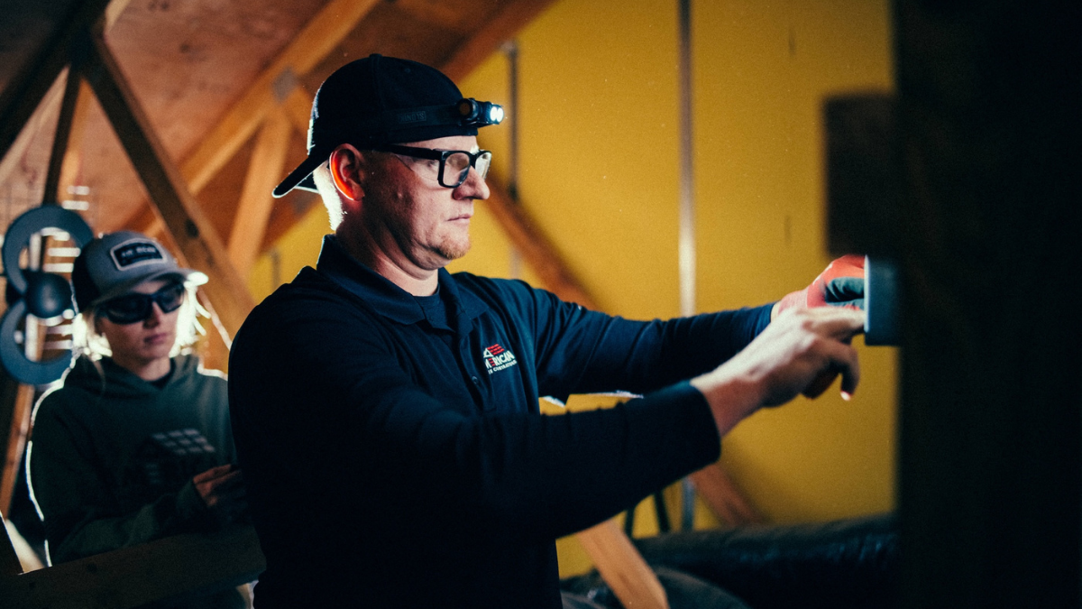 Field technician working inside an attic at a job site.