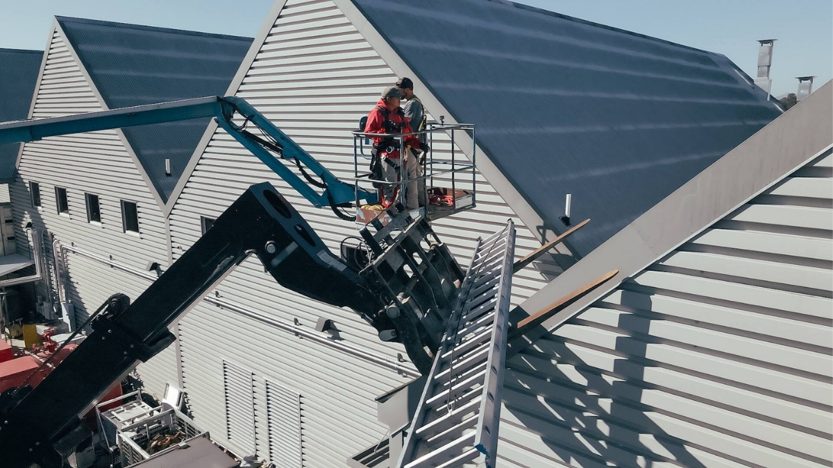 Solar contractors installing rooftop panels with aerial lift equipment.