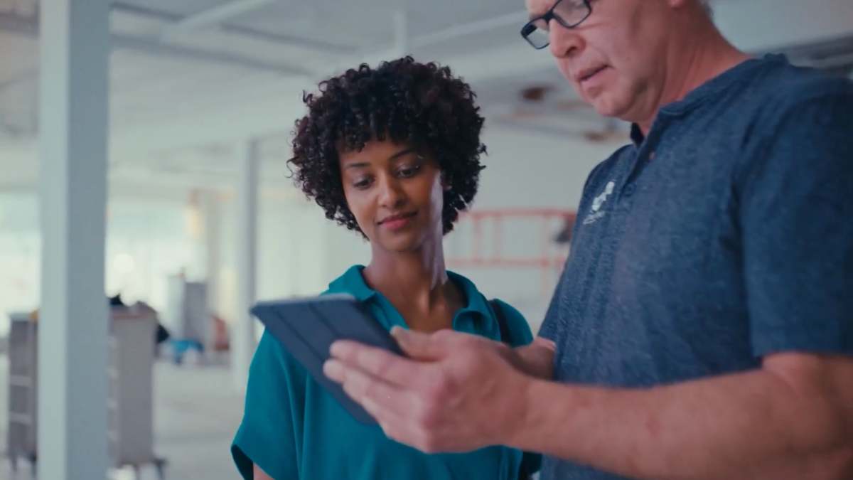 Contractor reviews project photos with client using tablet inside renovation space.