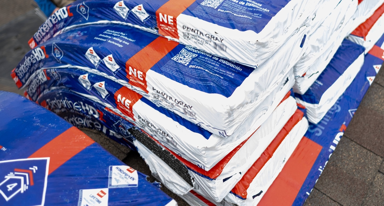 Stacks of roofing materials with manufacturer QR codes that contractors can scan to access product information, installation guides, and track materials on the job site.