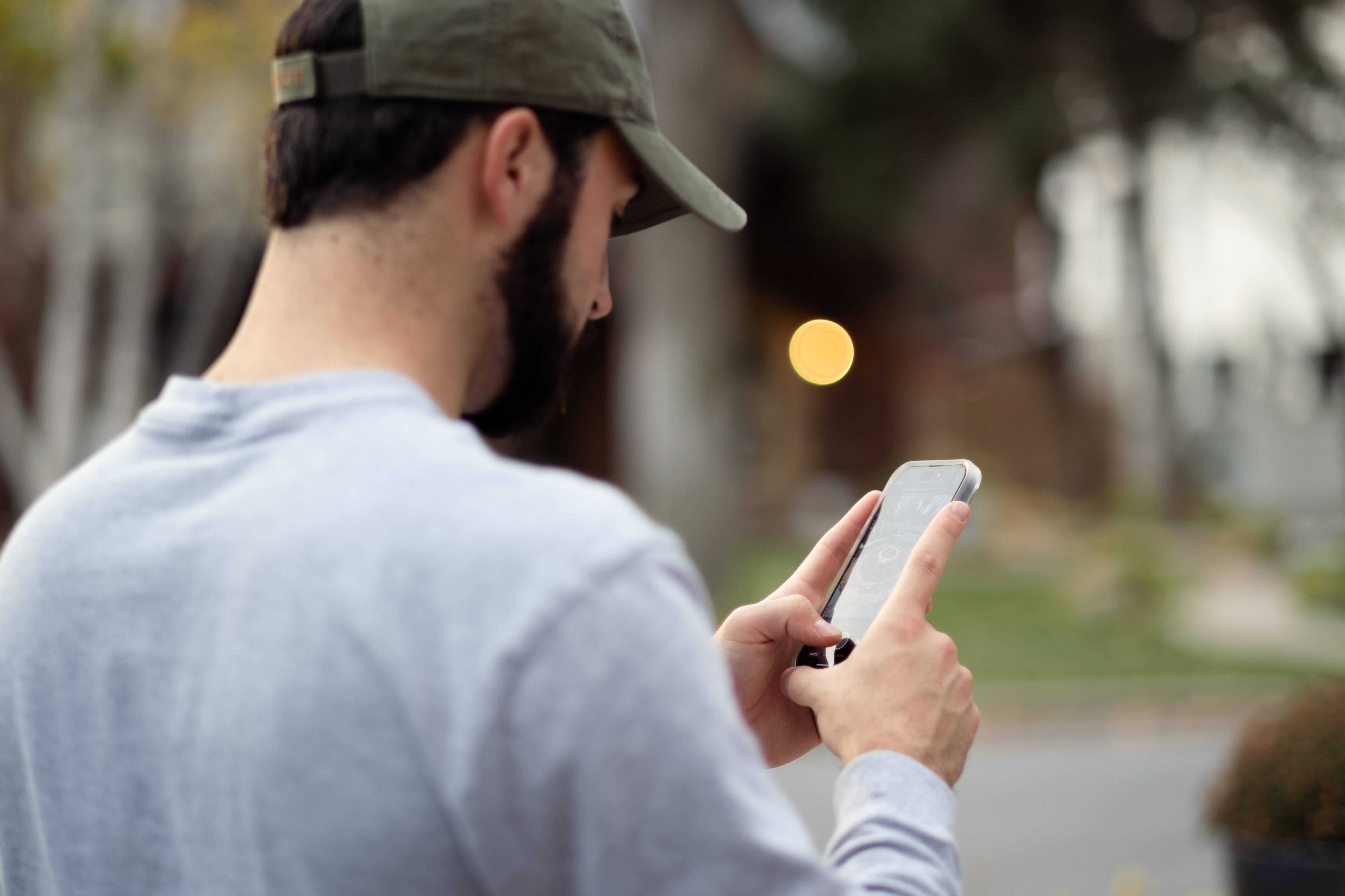 Field worker reviews project details on mobile app while documenting exterior job site conditions.