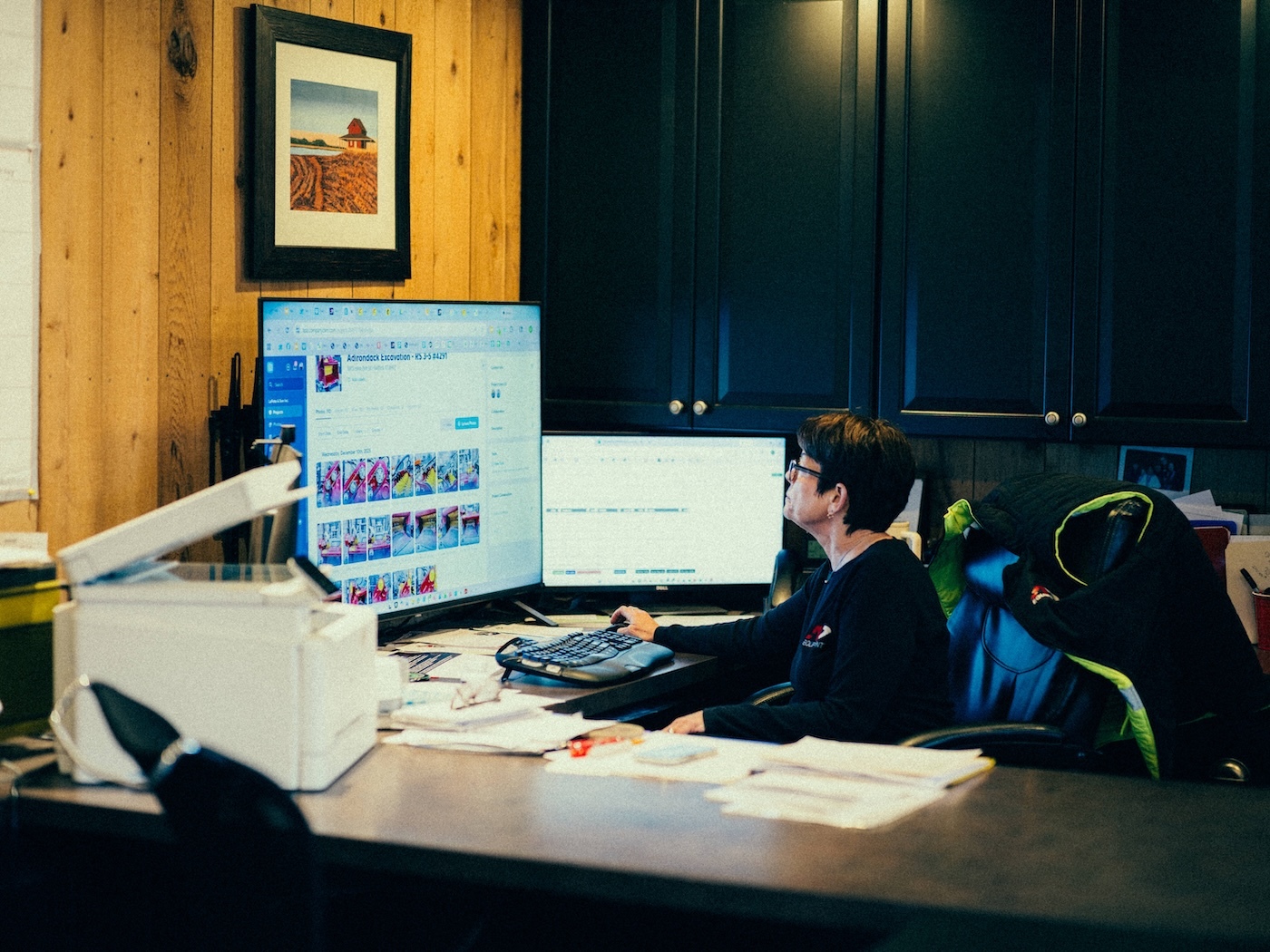 Office staff reviews project photos on desktop computer.