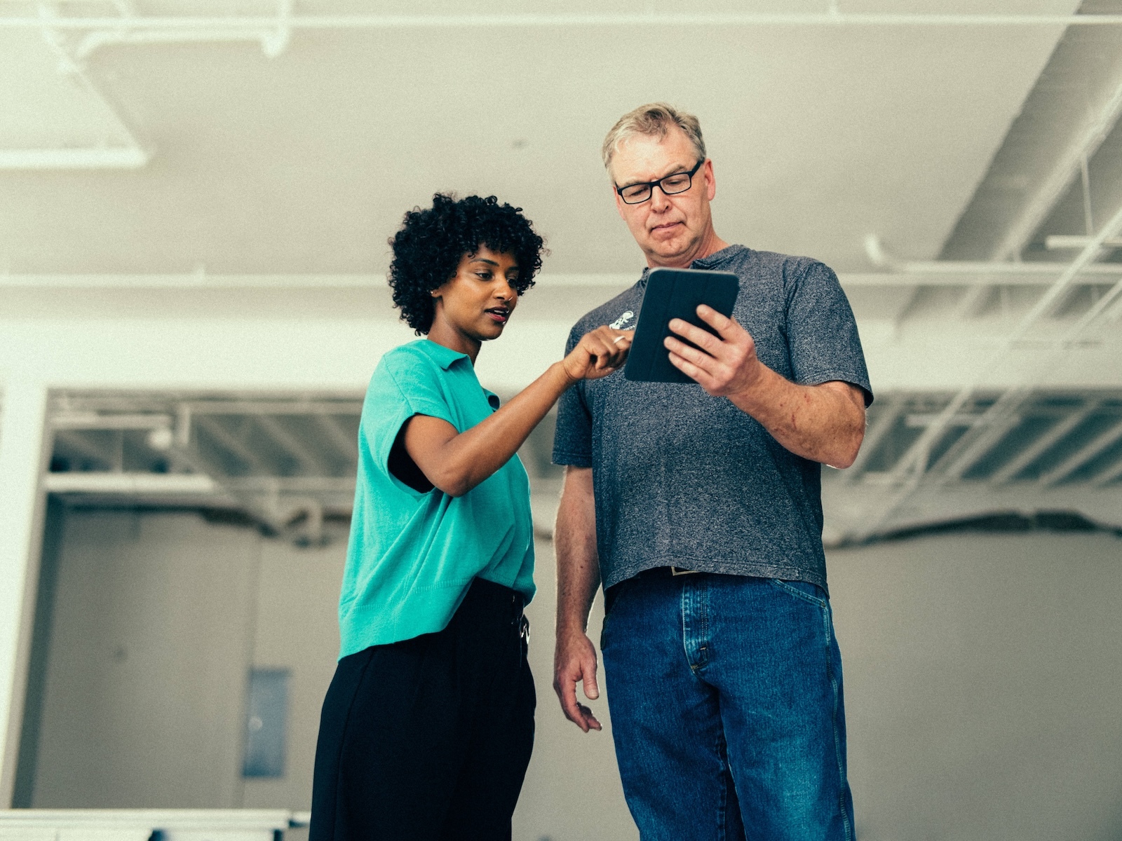 Crew members review project details on a tablet while inspecting interior commercial renovation space.