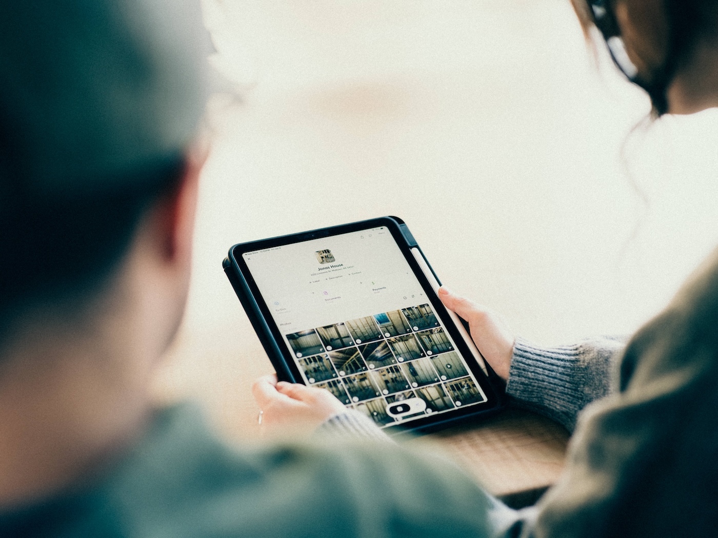 Contractors review job site photo grid in mobile app during project discussion.