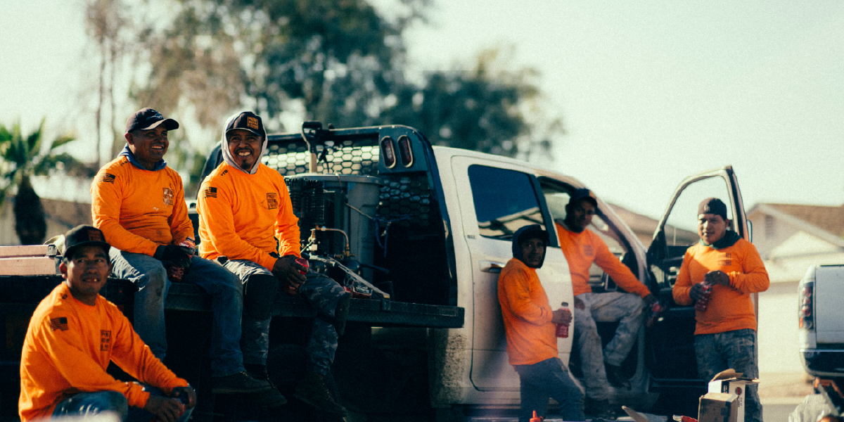 Group of construction workers laugh while they take a break beside a work truck.